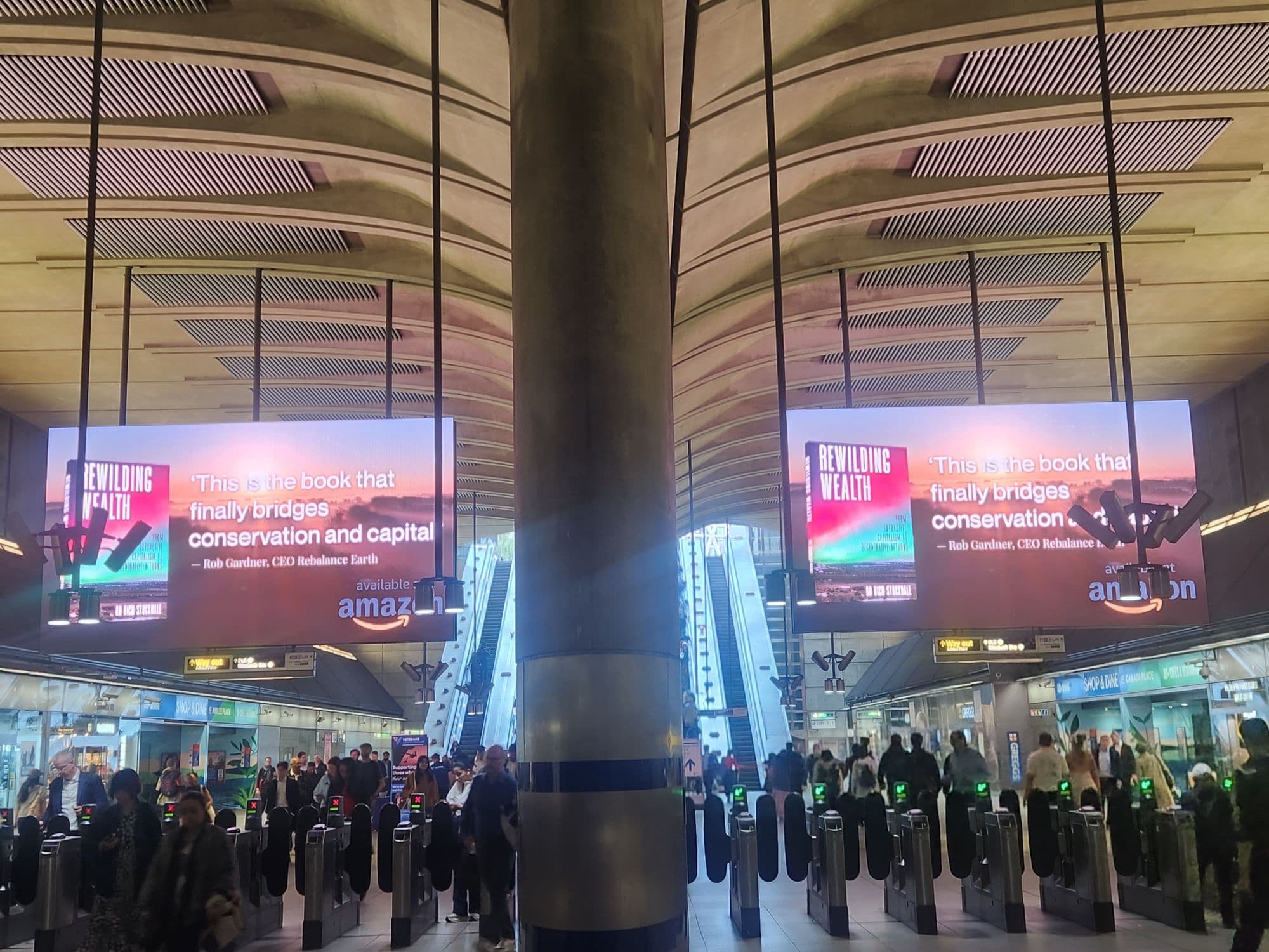 Commuters passing under the Rewilding Wealth creative on the Canary Wharf Digital Gateway