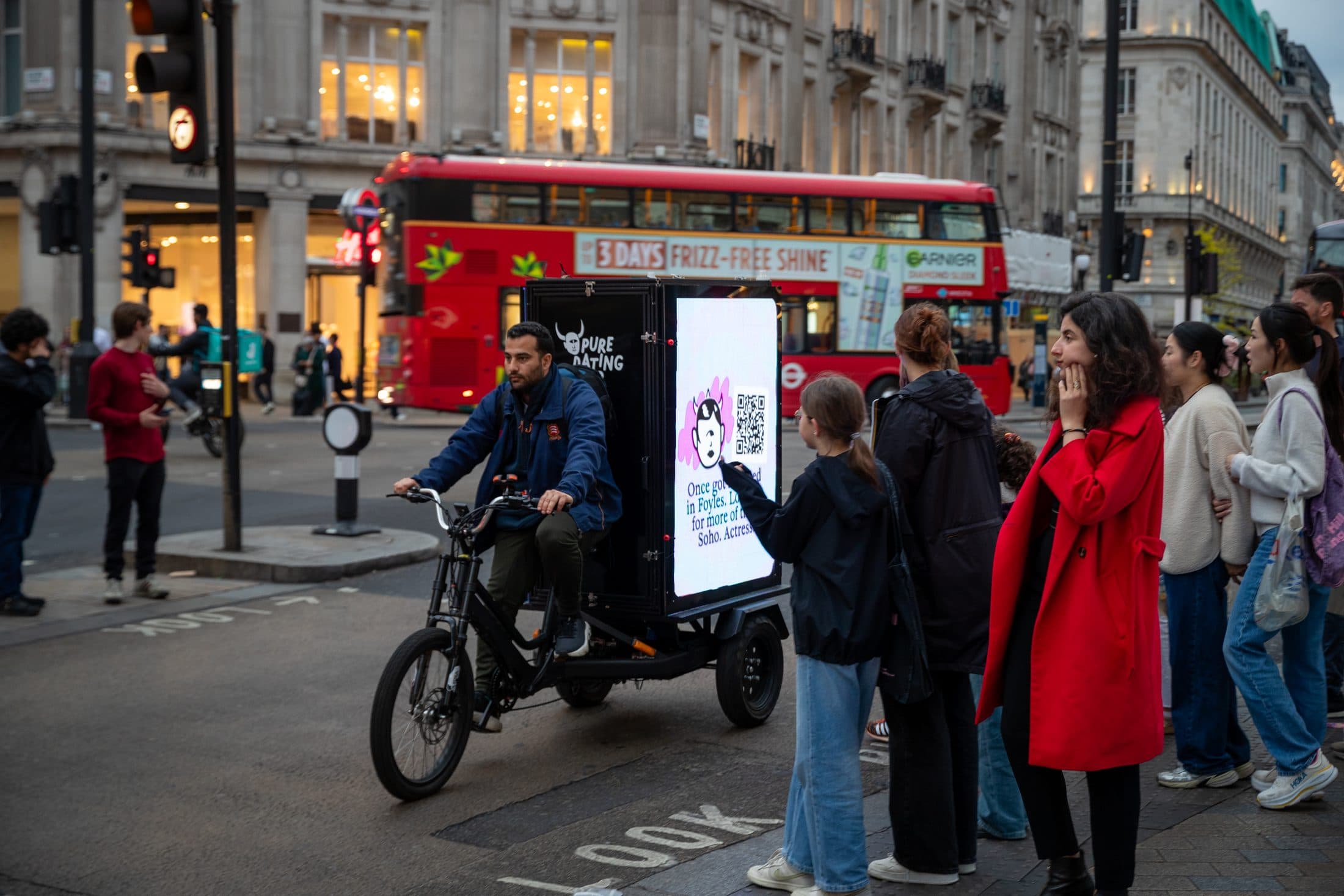 Pure AdBike on Oxford Street at dusk with the LED screens lit