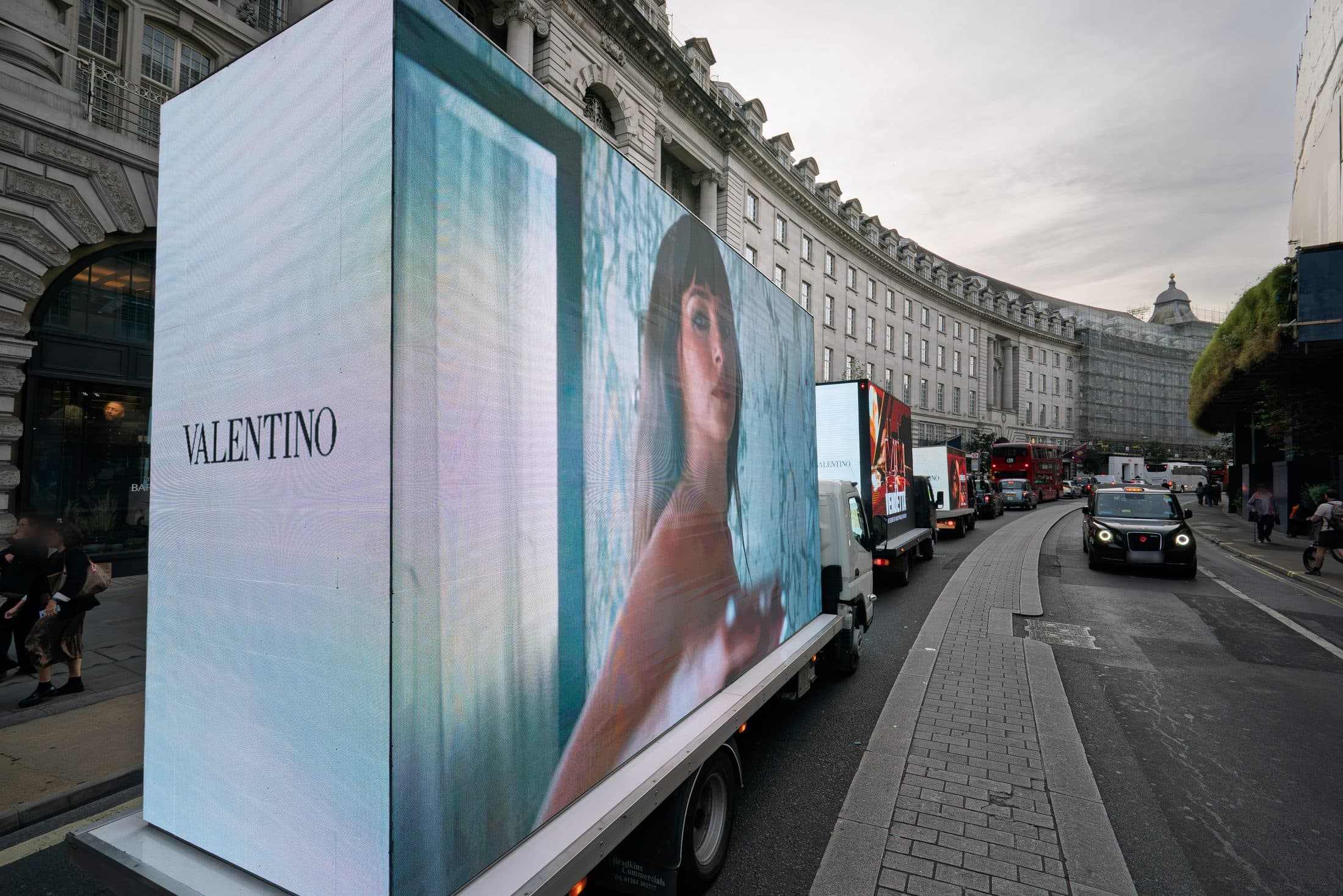 The VALENTINO wordmark on the rear screen of a Monster Digital AdVan on Regent Street, with the convoy ahead on the curve