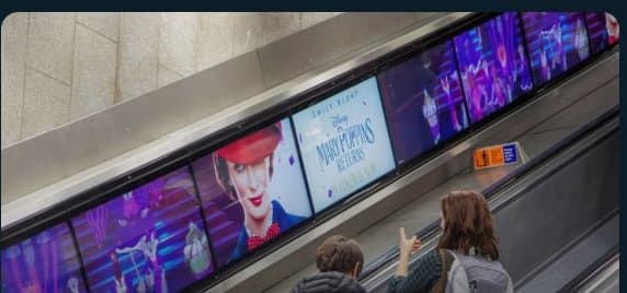 Digital ribbon panels running alongside a London Underground escalator