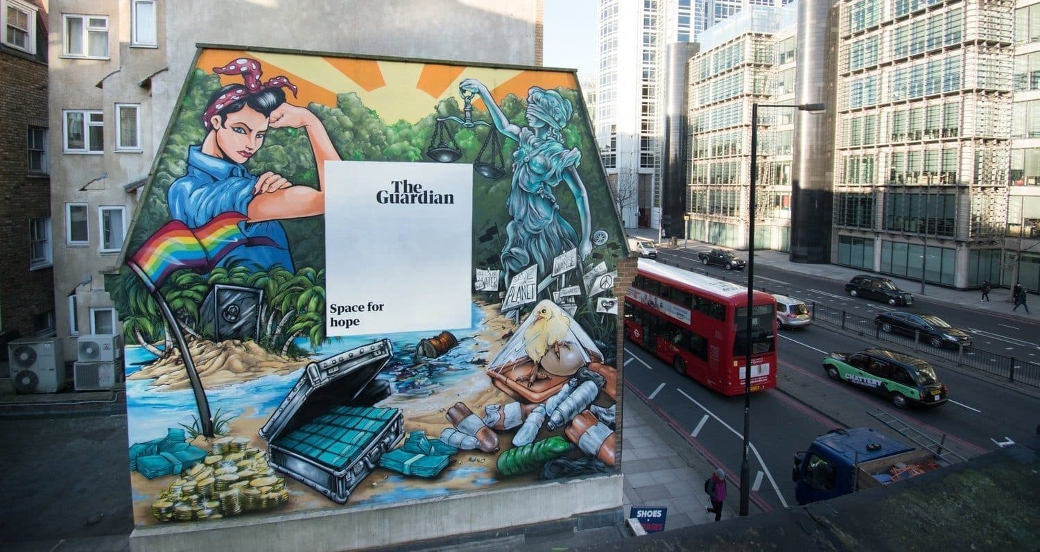 Large hand painted brand mural covering a building wall beside a busy London street