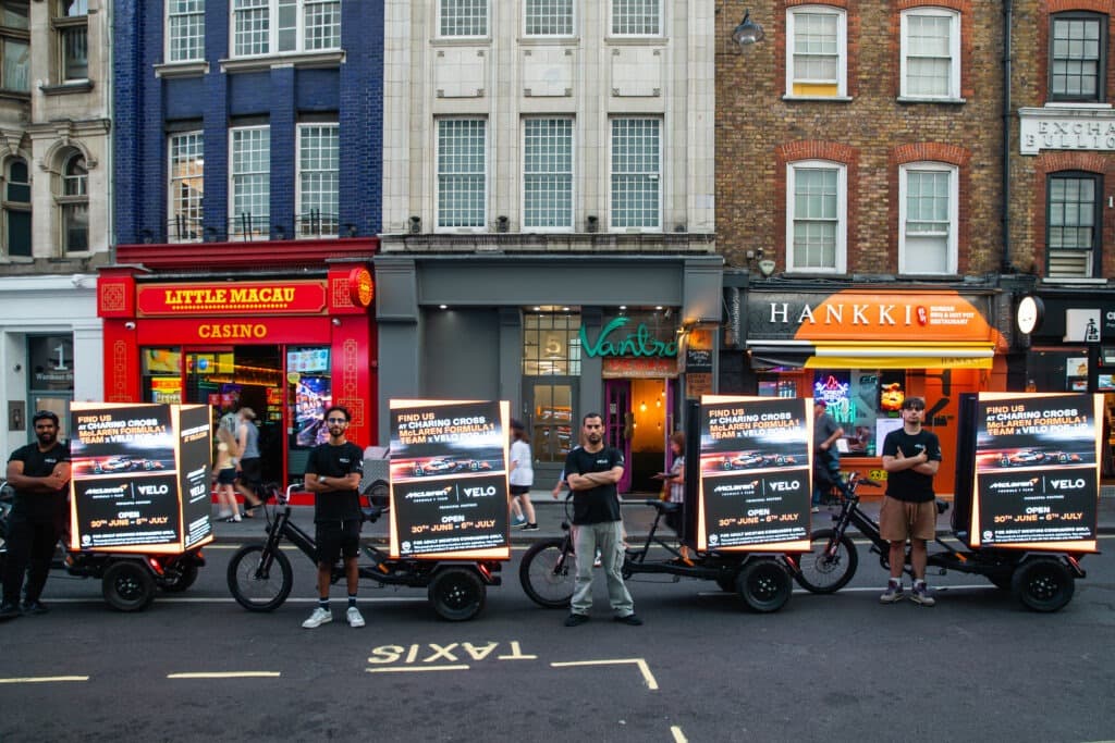 Velo x McLaren F1 Digital Billboard Bike at street level in the West End