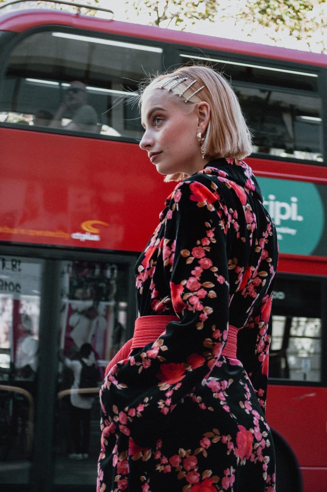 Shopper walking past a red double-decker bus carrying a side advertising panel